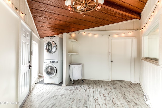 clothes washing area with stacked washer and clothes dryer, light wood finished floors, laundry area, visible vents, and wooden ceiling