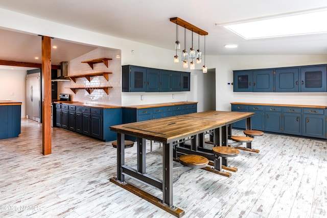 kitchen with blue cabinets, backsplash, stainless steel built in refrigerator, and light wood finished floors