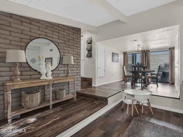 interior space featuring a notable chandelier, beam ceiling, baseboards, and wood finished floors