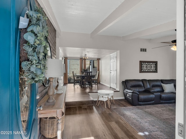 living area featuring visible vents, wood finished floors, beamed ceiling, baseboards, and ceiling fan with notable chandelier