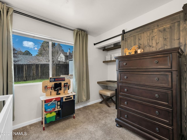 bedroom with light carpet, a barn door, and baseboards