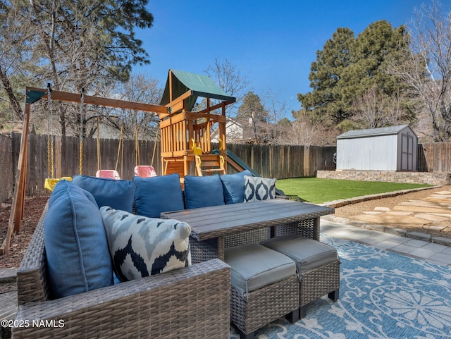 view of patio / terrace with a fenced backyard, an outdoor structure, a playground, and a shed