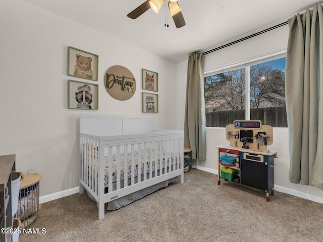 carpeted bedroom with ceiling fan, a crib, and baseboards