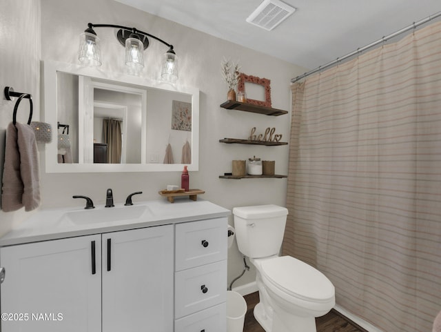 bathroom with visible vents, toilet, wood finished floors, curtained shower, and vanity