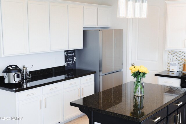 11941 Pegasus Rd, Bellemont, AZ 86015 - kitchen with freestanding refrigerator, white cabinetry, dark stone countertops, and backsplash