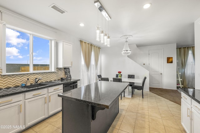 kitchen with a breakfast bar, sink, white cabinetry, a kitchen island, and pendant lighting