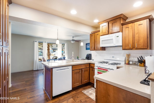 kitchen featuring dark wood-style floors, light countertops, brown cabinetry, white appliances, and a peninsula