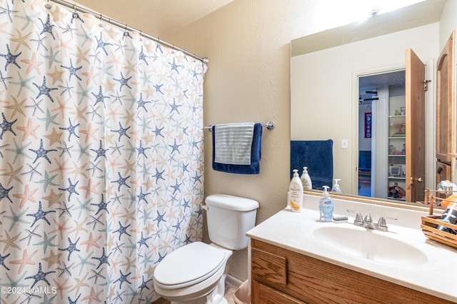 bathroom featuring curtained shower, a textured wall, vanity, and toilet