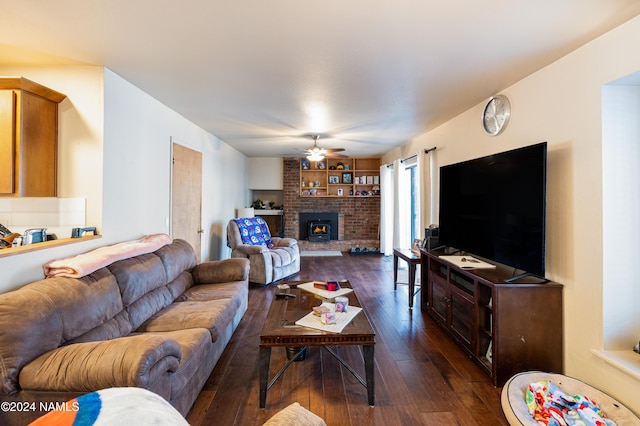 living area with dark wood-style floors, a brick fireplace, and a ceiling fan