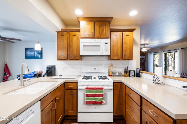 kitchen with white appliances, brown cabinets, a sink, and a peninsula