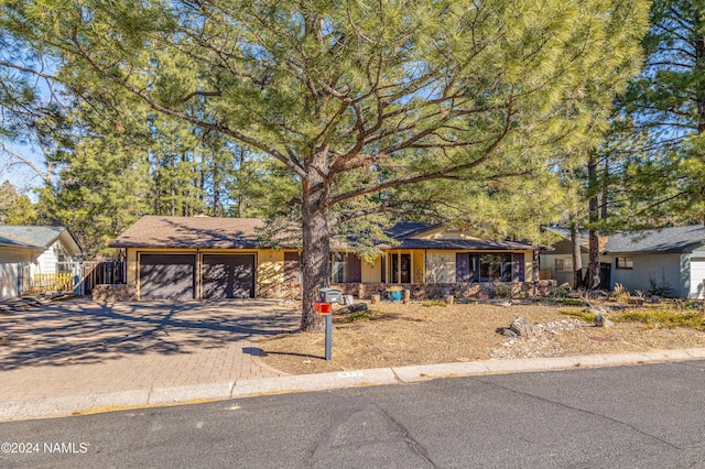 view of front facade featuring decorative driveway, fence, and an attached garage