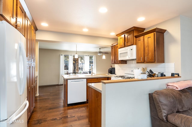 kitchen featuring dark wood-type flooring, brown cabinetry, open floor plan, white appliances, and a peninsula