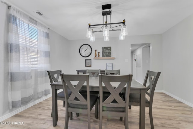 dining space featuring an inviting chandelier and light wood-type flooring