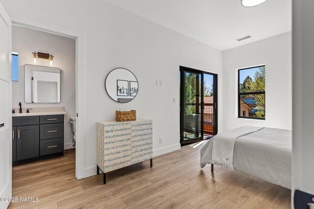 302 W Oak Ave Unit 1, Flagstaff, AZ 86001 - bedroom featuring access to exterior, light wood finished floors, a sink, connected bathroom, and baseboards