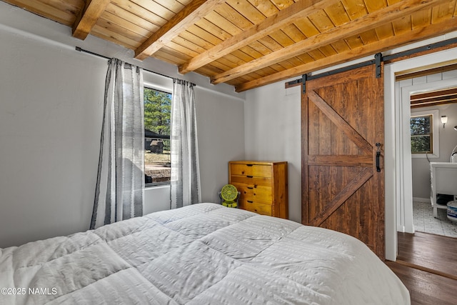 5552 White Tail Ln, Flagstaff, AZ 86005 - bedroom with a barn door, wood finished floors, multiple windows, and beamed ceiling