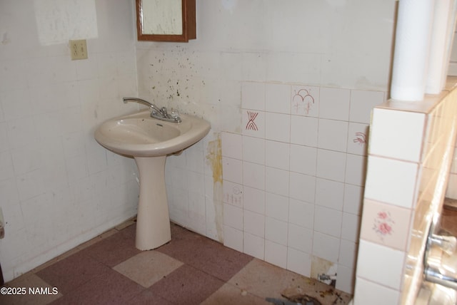 bathroom with a sink and tile walls