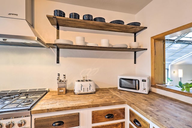 kitchen with cooktop, wooden counters, and wall chimney exhaust hood