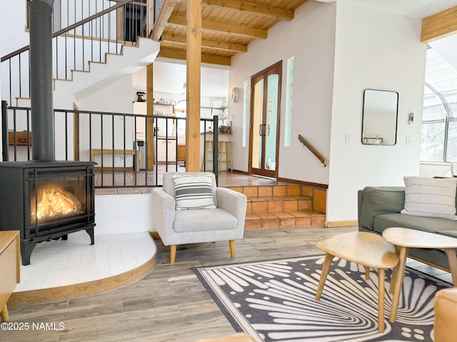 living room featuring wood ceiling, beamed ceiling, wood-type flooring, and a wood stove