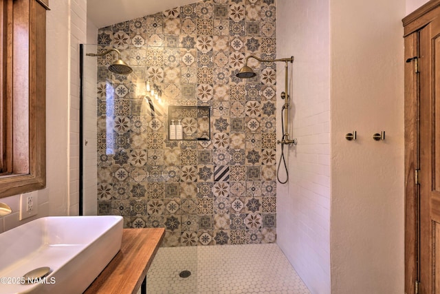 bathroom featuring tiled shower, lofted ceiling, and sink