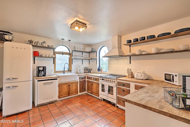 kitchen featuring light tile patterned flooring, ventilation hood, sink, hanging light fixtures, and white appliances