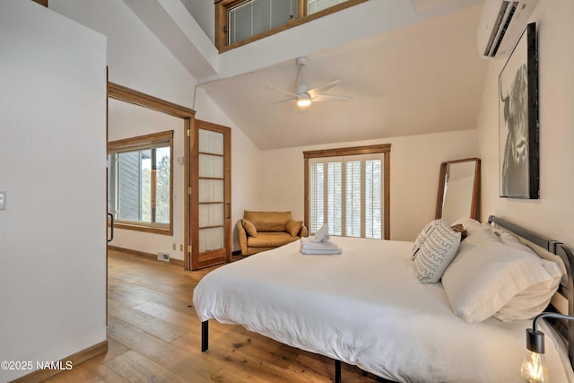 bedroom featuring lofted ceiling, light hardwood / wood-style flooring, a wall unit AC, and ceiling fan