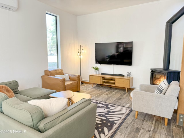 living room featuring hardwood / wood-style flooring, a wall mounted air conditioner, and a wood stove