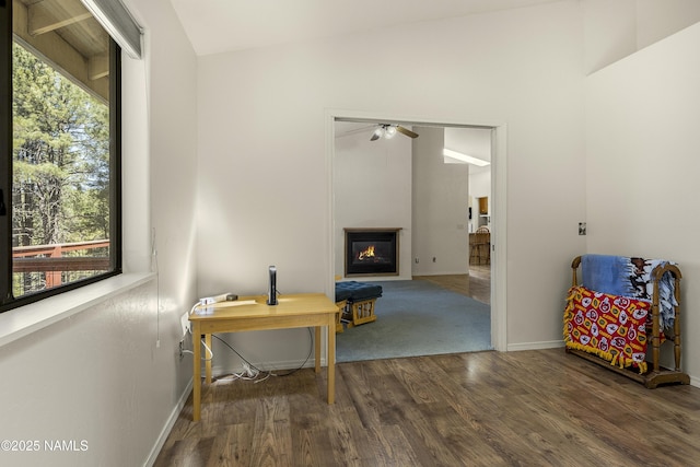sitting room with vaulted ceiling, baseboards, a ceiling fan, a glass covered fireplace, and wood finished floors