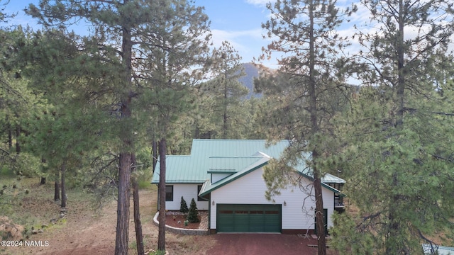 view of front facade with metal roof, a garage, driveway, and a standing seam roof