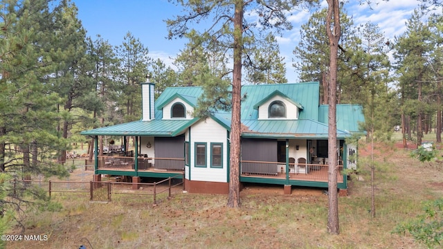 back of property with metal roof, fence, and a chimney