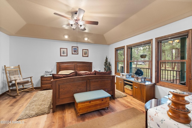 bedroom featuring a raised ceiling, light wood-style flooring, and baseboards