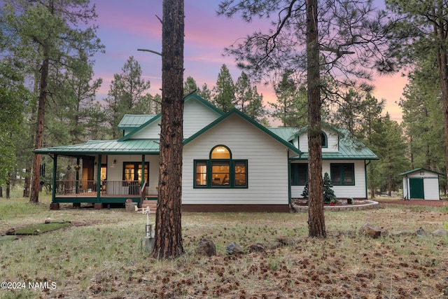 back of property with a shed, a standing seam roof, a porch, an outdoor structure, and metal roof