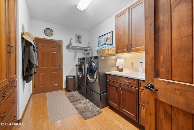 laundry area with cabinet space, washer and dryer, and light wood-type flooring