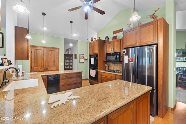 kitchen with brown cabinets, black appliances, a sink, tasteful backsplash, and a peninsula