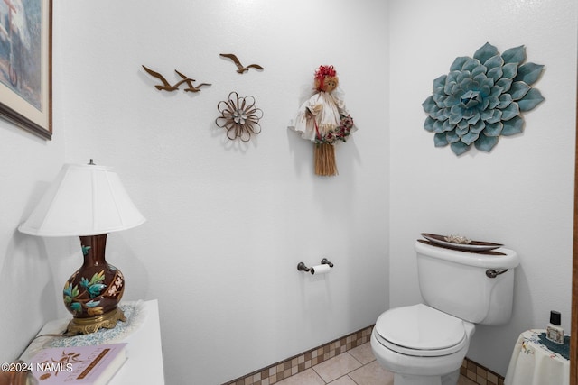 half bath with tile patterned floors, toilet, and baseboards