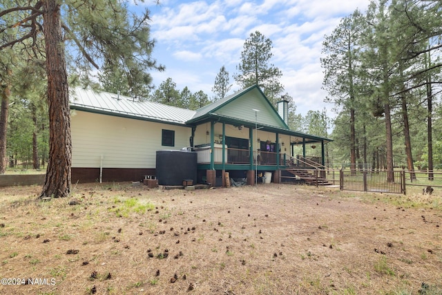 rear view of property with a chimney, metal roof, a standing seam roof, and fence