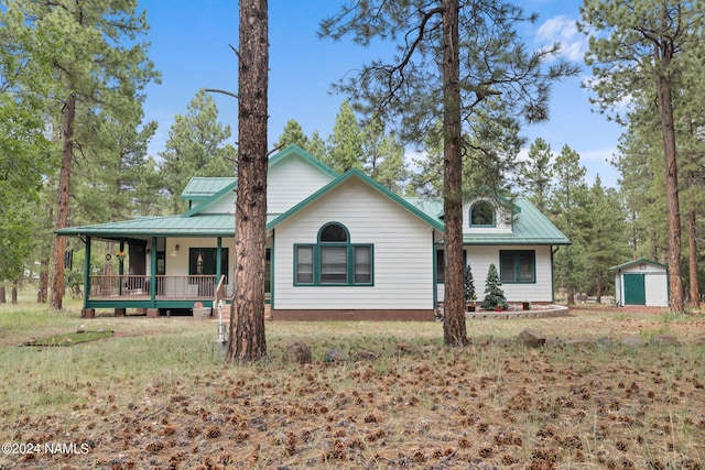 rear view of property with a shed, a porch, metal roof, an outbuilding, and a standing seam roof