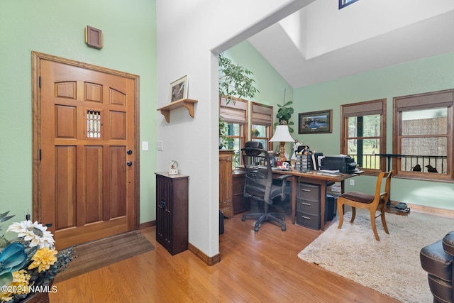 office with baseboards, high vaulted ceiling, and wood finished floors