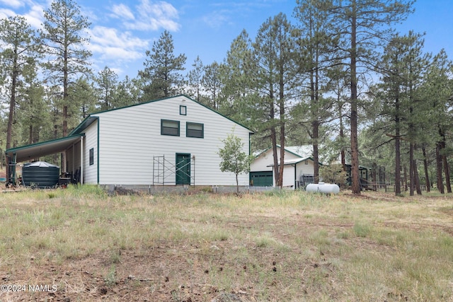 view of side of home featuring an outdoor structure, a carport, and a detached garage