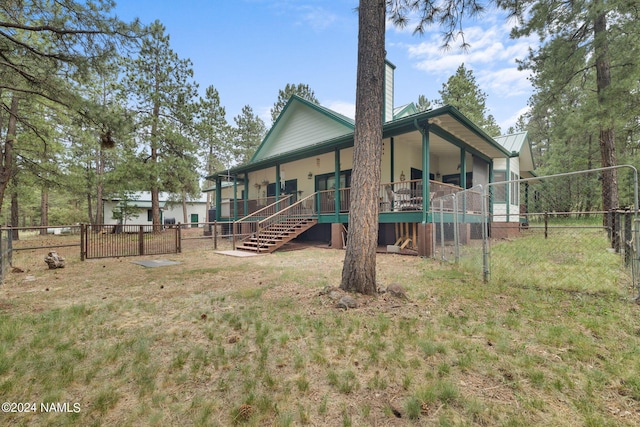 back of house with metal roof, a yard, stairs, and fence