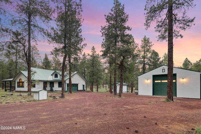 yard at dusk featuring a storage shed, an outdoor structure, a garage, and dirt driveway