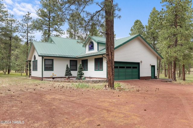 view of front of property with an attached garage, metal roof, and dirt driveway