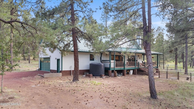 view of front of house with a garage, covered porch, metal roof, and fence