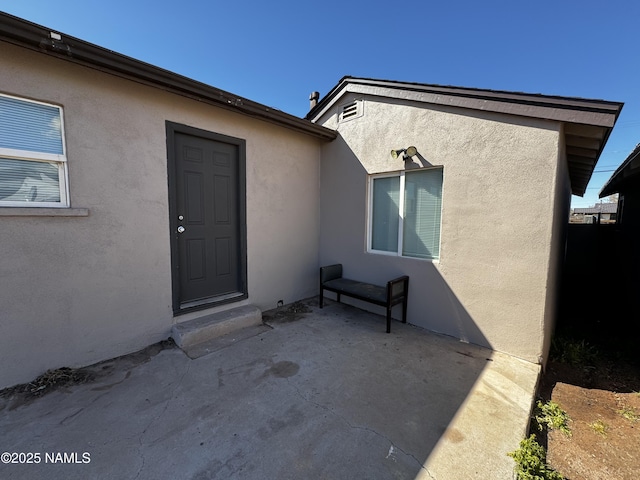 property entrance with a patio area and stucco siding