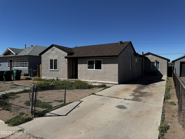 view of front of property with driveway, roof with shingles, fence, and stucco siding