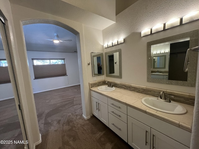 bathroom with double vanity, a ceiling fan, baseboards, and a sink