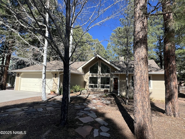 view of front of property featuring a garage, concrete driveway, and roof with shingles