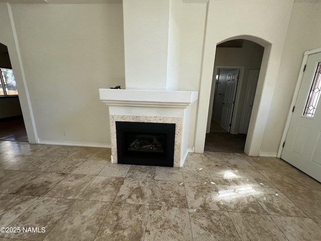 unfurnished living room with arched walkways, baseboards, and a fireplace