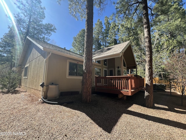 rear view of property featuring a wooden deck and a shingled roof