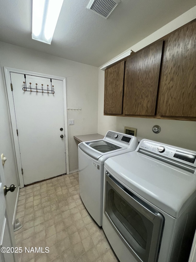 laundry area featuring light floors, visible vents, separate washer and dryer, and cabinet space