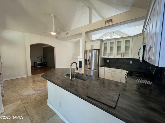 kitchen featuring dark countertops, stainless steel appliances, arched walkways, and a sink